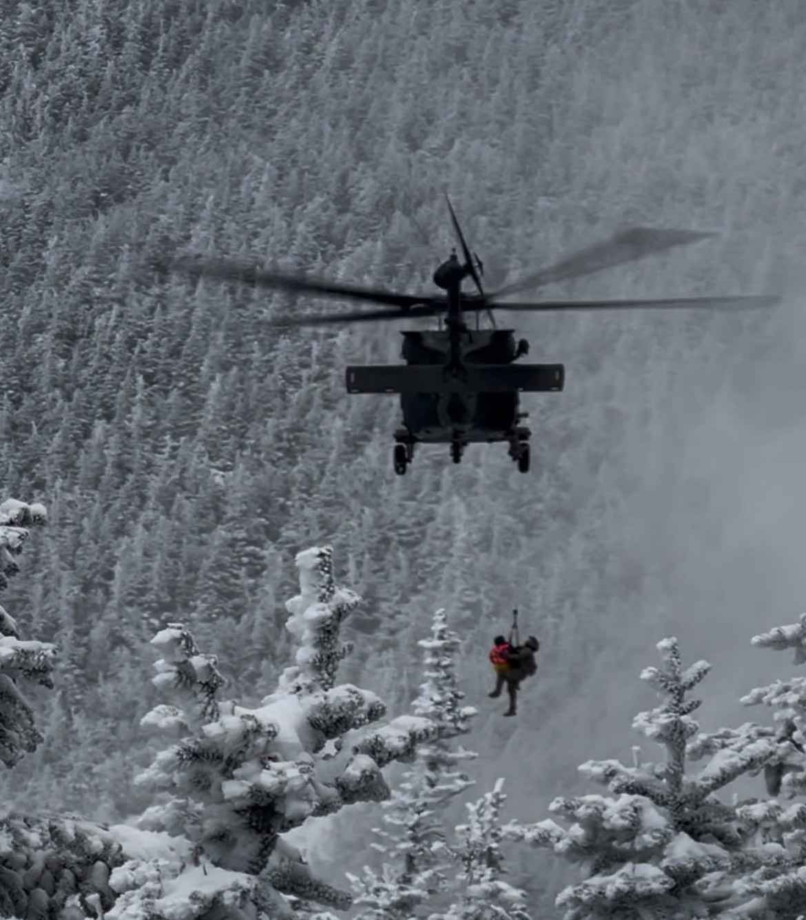 An Army National Guard helicopter hoists a hypothermic hiker near Little Haystack in New Hampshire. (NH Fish and Game Photo)